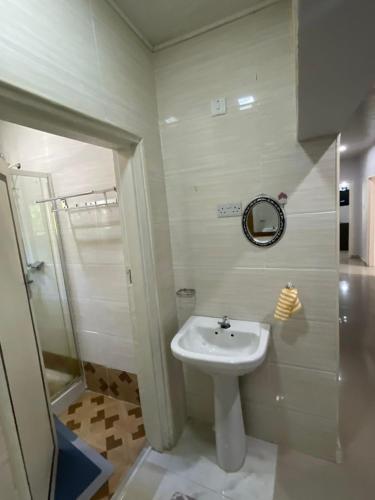 a white bathroom with a sink and a mirror at Elimisam stays in Kitwe
