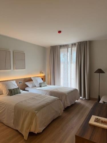 a hotel room with two beds and a window at Hotel La Palloza in Lugo