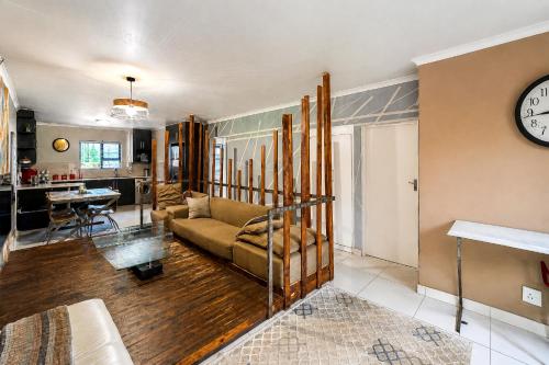 a living room with a couch and a clock on the wall at Swallows Nest Haven in Boksburg
