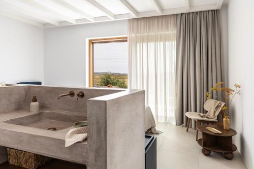a bathroom with a large concrete sink and a window at ROOTS Nature Living Milos in Adamantas