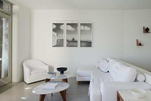 a white living room with a white couch and two chairs at Grace Hotel, Auberge Collection in Imerovigli