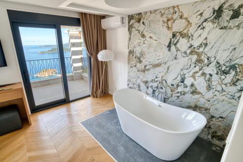 a bathroom with a white tub and a stone wall at Quercus Villa 2 in Blizikuće