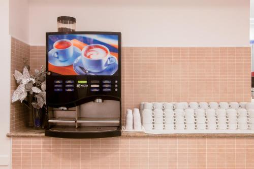 een drankautomaat op een tegelwand met een koffiezetapparaat bij Hotel Delle Nazioni in Cesenatico
