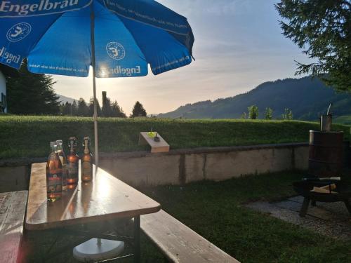 a picnic table with bottles on it with an umbrella at Hochtal Apartments in Tannheim