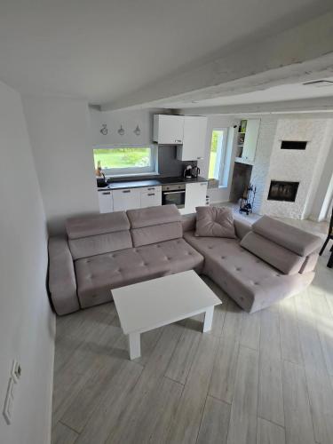 a living room with a brown couch and a white table at D&A Vila - Private Villa with Sauna & Hot Tub in Arciūnai