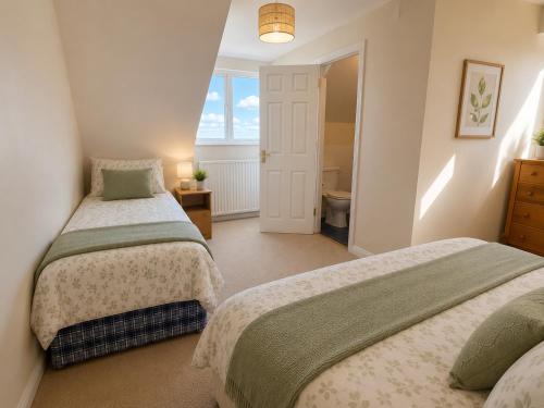 a bedroom with two beds and a bathroom at Tullyally House in Castle Cary