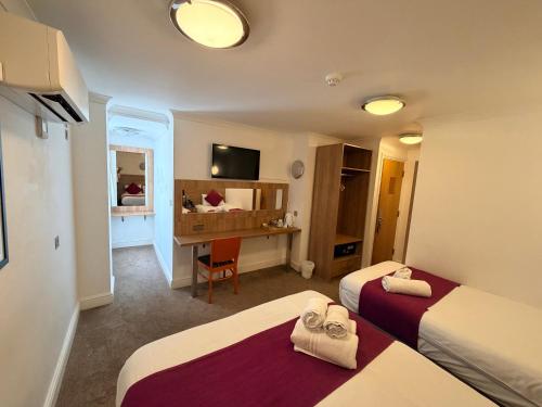 a hotel room with two beds and a desk at Elysee Hyde Park in London
