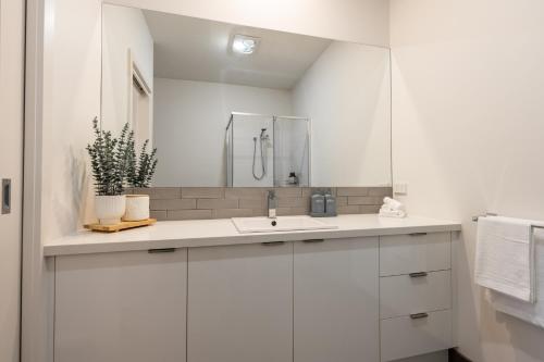a white bathroom with a sink and a mirror at Shell Escape at Ocean Grove in Ocean Grove