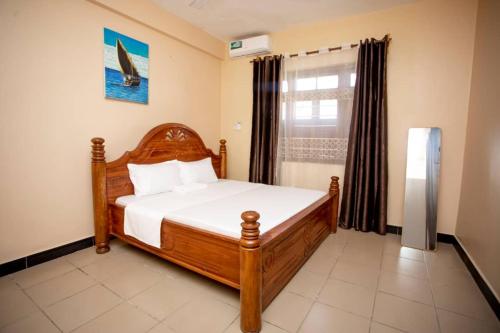 a bedroom with a wooden bed and a window at Daf House in Zanzibar City