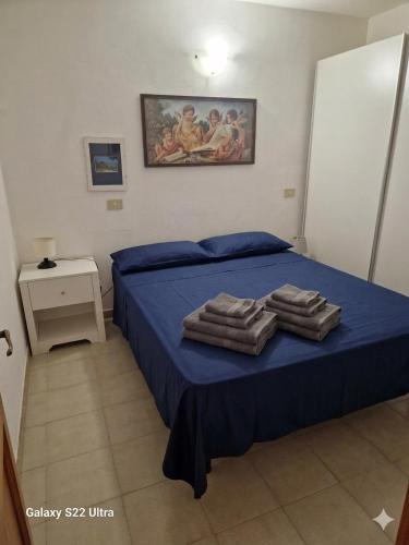 a bedroom with a bed with blue sheets and towels at San Teodoro Appartamento Vacanze Centro in San Teodoro