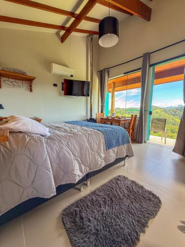 a bedroom with a bed and a large window at Altos da Mantiqueira Chalés -Grupo Vertentes in Santo Antônio do Pinhal