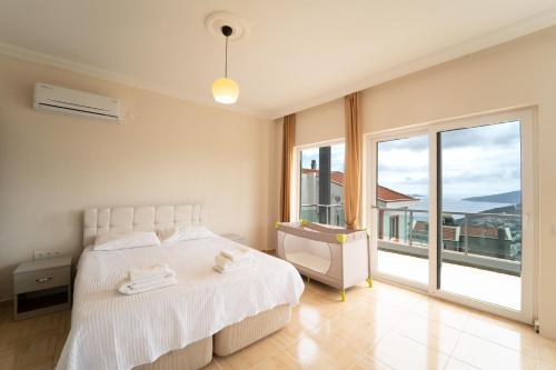 a bedroom with a white bed and a large window at Villa Mevsim in Kaş