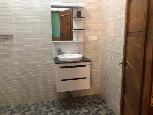 a bathroom with a sink and a mirror at Chez Roseline in Ndangane