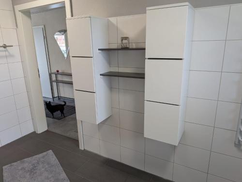 a white kitchen with white cabinets and a doorway at Pfoten & Komfort Barrierefrei in Butjadingen