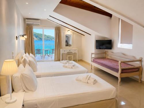two beds in a room with a view of the ocean at Akrogiali Studios - Nidri, Lefkada in Nydri