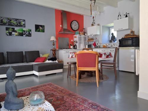a living room and kitchen with a couch and a table at Les volets bleus in Prémian