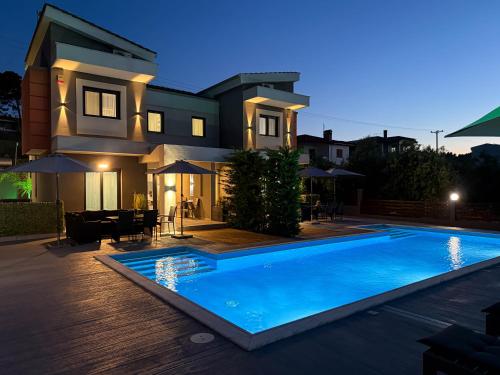 a house with a swimming pool in front of a house at Assos Luxury Villas in Pefkochori