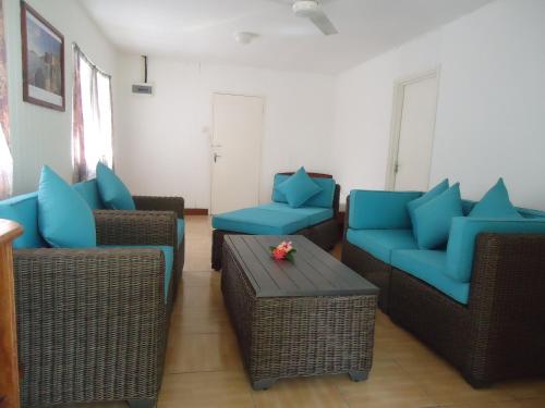 a living room with blue chairs and a table at Chez Michellin Pensions Residence in La Digue