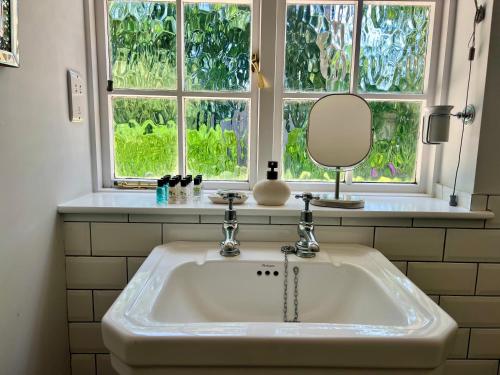a bathroom sink with a mirror and a window at The Priory Cottage in Legbourne