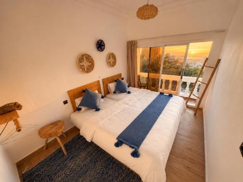 a bedroom with two beds and a large window at Happy Waves Morocco - Surf Hostel Tamraght in Tamraght Ou Fella