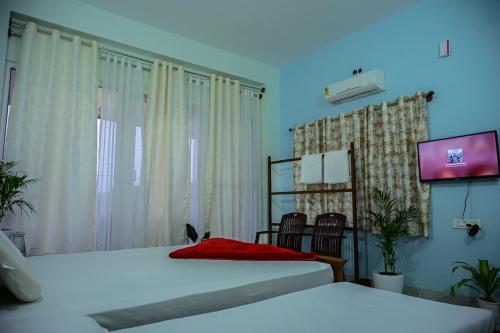 a bedroom with two beds and a flat screen tv at Coorg Manam Homestay in Kushālnagar