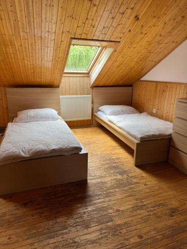 two beds in a bedroom with a wooden ceiling at Apartment sklep 33E in Hrušky