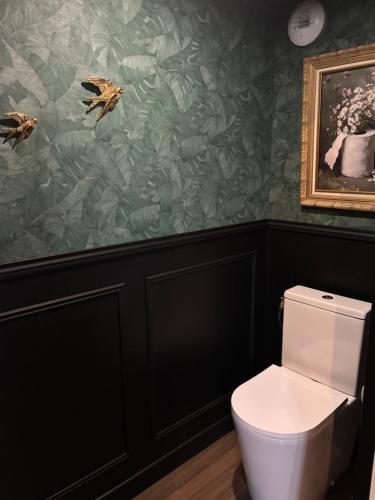 a bathroom with a white toilet and green wallpaper at L atelier de Jules in Lyon