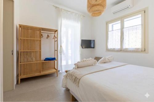 a white bedroom with a large bed and a window at la perla sul mare in Sampieri