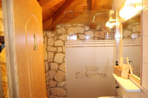 a bathroom with a toilet and a stone wall at Villa Socrates in Vasilikos