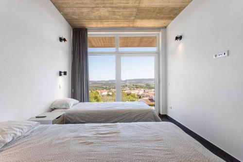 two beds in a room with a large window at Colina do Sol 2 in Amoreira
