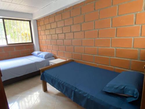 a room with two beds and a brick wall at Finca Panoramica in Barbosa