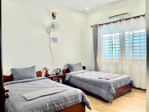 a bedroom with two beds and a window at Pkar Thmor Siem Reap Guest House in Phumĭ Réach Born (2)