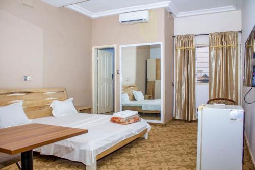 a hotel room with two beds and a refrigerator at NIF-UR Hotel Bohicon in Bohicon