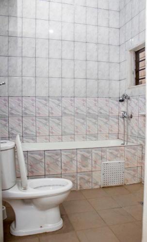 a bathroom with a toilet and a bath tub at NIF-UR Hotel Bohicon in Bohicon