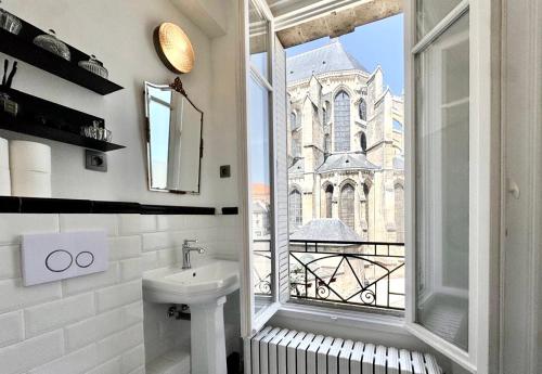 a bathroom with a sink and a window with a church at La Cathédrale in Soissons