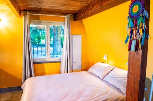 a yellow bedroom with a bed and a window at Il Casotto tra i Vigneti in Nizza Monferrato