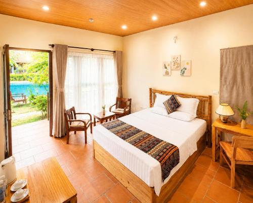 a bedroom with a bed and a desk and a window at Wildland Resort in Phú Quốc