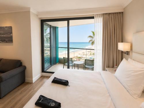 a hotel room with a bed and a view of the ocean at Herbert Samuel Okeanos Suites Herzilya in Herzliya