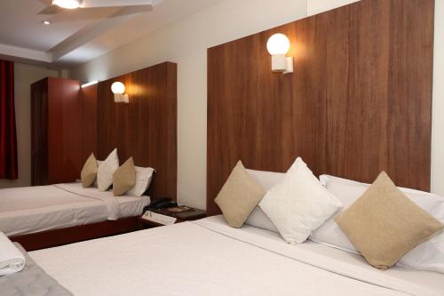 a hotel room with two beds with white pillows at Dhanunjayas Luxury Hotel in Hosūr