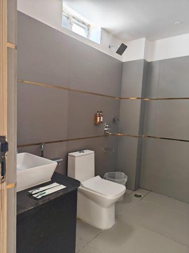 a bathroom with a white toilet and a sink at Trivera in Pidugurālla