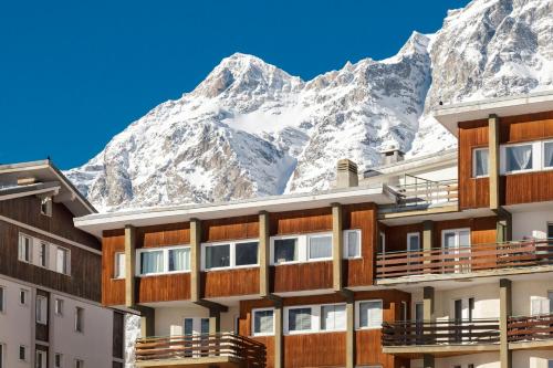 a hotel with snow covered mountains in the background at Maison Rêve Blanc - Panoramic Ski in - Ski out in Breuil-Cervinia