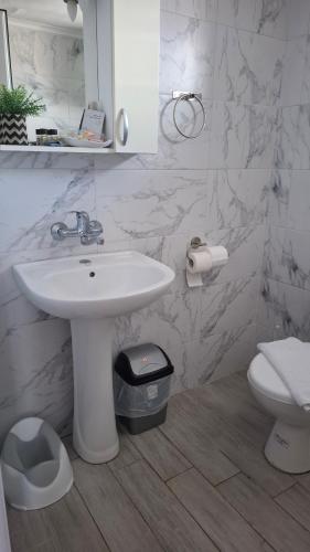 a white bathroom with a sink and a toilet at Gatos Village Studios & Apartments in Asprovalta