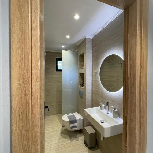 a bathroom with a sink and a toilet and a mirror at Μπουκαμβίλια - Bougainvillea in Sivota