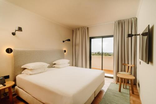 a bedroom with a white bed and a large window at Vale d'El Rei Hotel & Villas in Carvoeiro
