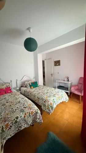 a bedroom with two beds and a pink chair at Apartamento MILA centro in Comillas