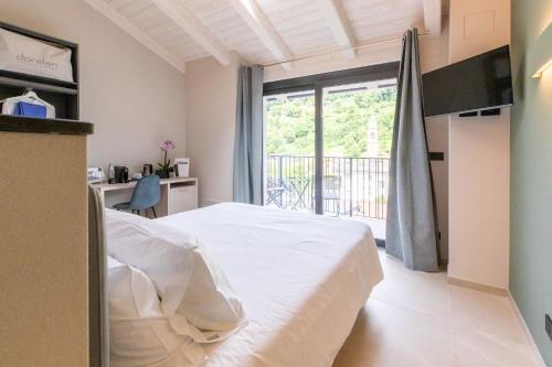 a bedroom with a white bed and a large window at La Collina delle Rondini in Boves