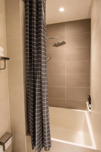 a bathroom with a tub and a shower curtain at Centraltique Veranda Living in Hanoi