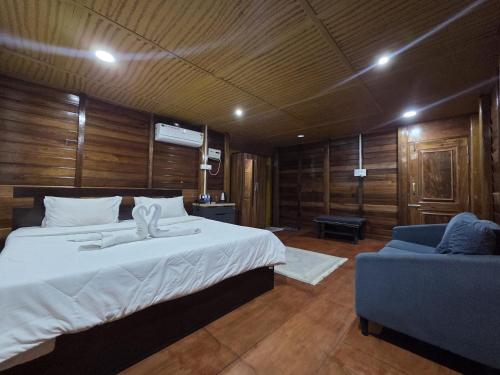 a bedroom with a large bed and a blue couch at Sopo Resort in Duimukh