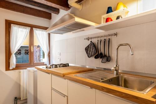 a kitchen with white cabinets and a sink at Erbe Canal View Private House in Venice
