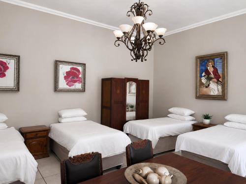 a room with three beds and a table and a chandelier at Alimento Guest House in Upington
